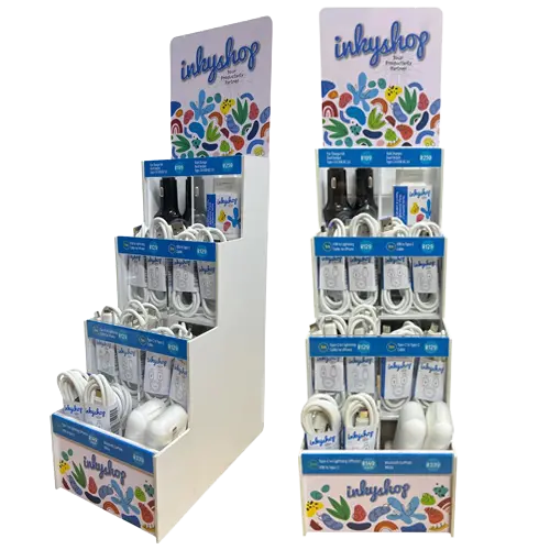 Two angles of a compact white countertop display stand from The Inky Shop filled with retail-ready USB, Type-C, and Lightning cables, car chargers, and ear pods, featuring colorful branding graphics.