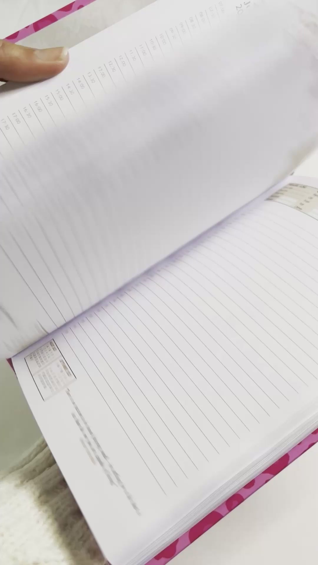 Person flipping through the blank pages of a5 page-a-day diary with hot pink cover design